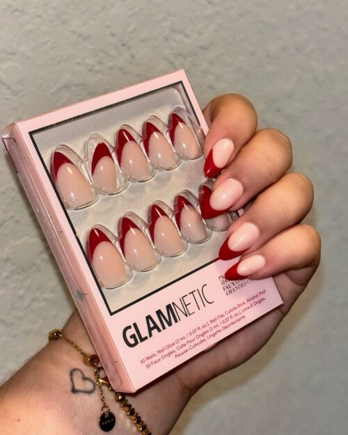 Hand holding a box of Glamnetic press-on nails with red and nude French tip design.