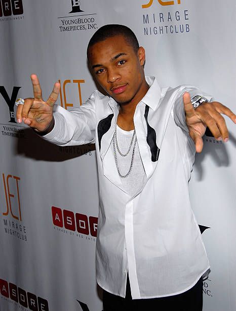 Bow Wow posing on a red carpet in a white shirt with peace signs.